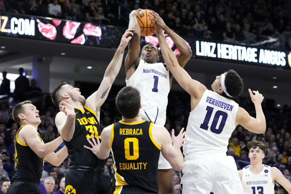 Northwestern guard Chase Audige (1) battles for a rebound against Iowa forward Payton Sandfort, left, guard Connor McCaffery, second from left, forward Filip Rebraca (0) and Northwestern forward Tydus Verhoeven (10) during the second half of an NCAA college basketball game in Evanston, Ill., Sunday, Feb. 19, 2023. (AP Photo/Nam Y. Huh)