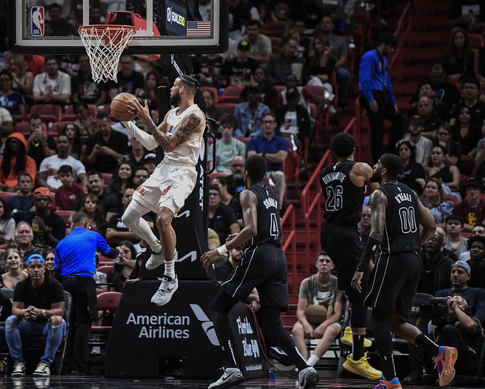 Miami Heat forward Caleb Martin, top, scores in front of Brooklyn Nets guard Edmond Sumner (4) during the first half of an NBA basketball game, Saturday, March 25, 2023, in Miami, Fla. (AP Photo/Michael Laughlin)