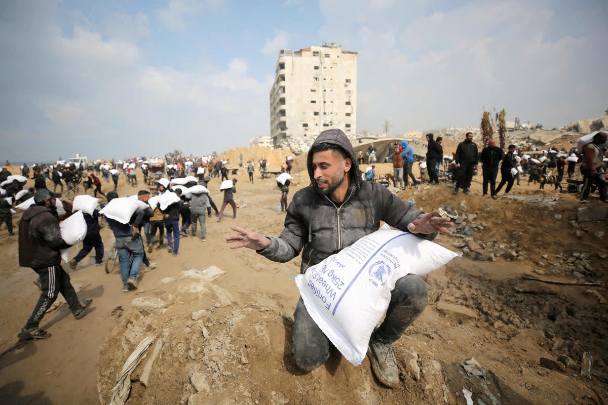 Palestinians carry bags of flour from an aid truck in Gaza City last month (Reuters)