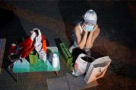 Street vendor Yan Ying sits behind her improvised stall after officials ordered her to leave following an outbreak of the coronavirus disease (COVID-19) in Beijing