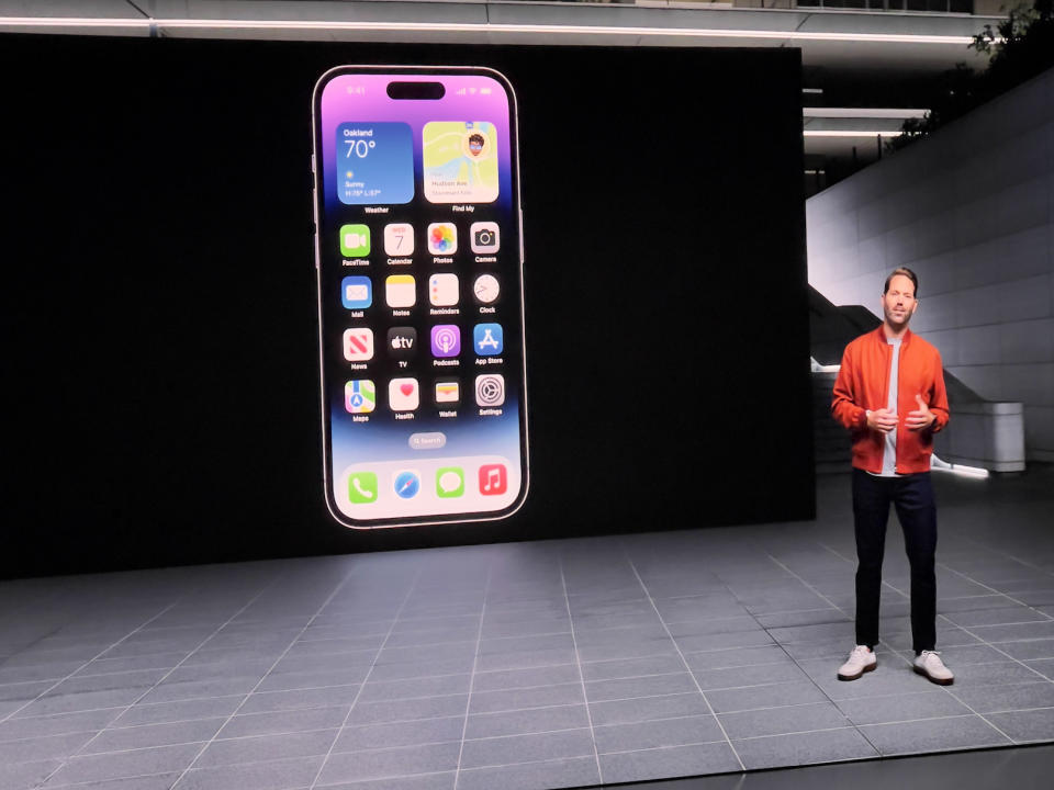 A screenshot of the iPhone 14 Pro reveal, with a presenter in an orange jacket talking about the phone.