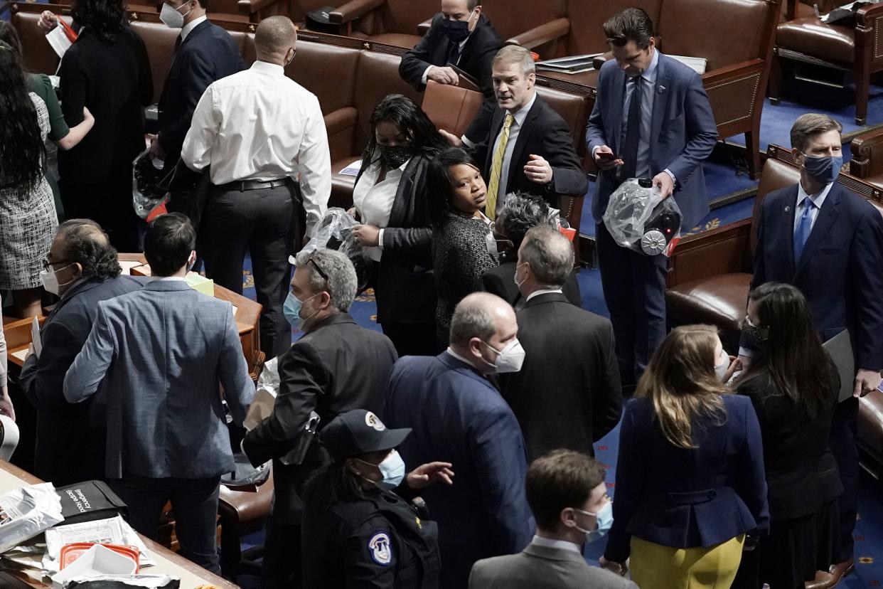 House of Representatives members leave the floor of the House chamber as protesters try to break into the chamber at the U.S. Capitol on Wednesday, Jan. 6, 2021, in Washington.