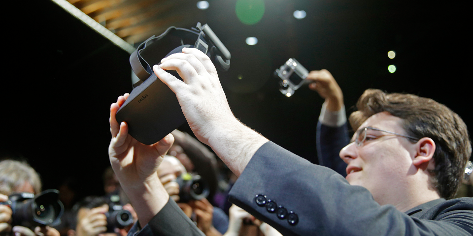 In this June 11, 2015 file photo, Oculus founder Palmer Luckey holds up the new Oculus Rift virtual reality headset for photographers following a news conference, in San Francisco. Luckey and other pioneers of modern virtual reality technology from such companies as Google and Sony are gathering for a summit on Wednesday, Feb. 10, 2016, about the immersive medium in Hollywood.