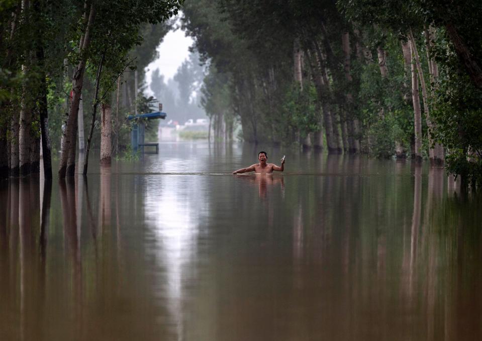 A local resident walks in chestdeep floodwaters towards a rescue boat near Zhuozhou, China. (Photo: Kevin Frayer/Getty Images)