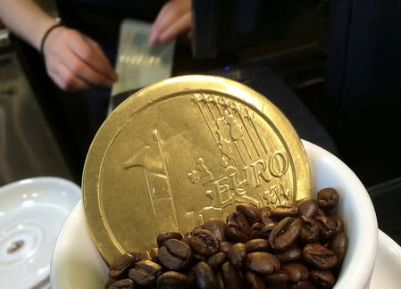An employee uses a cash till behind a chocolate shaped one Euro coin at a cafe in central London
