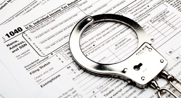 handcuffs on an American 1040 income tax form indicating tax fraud or evasion