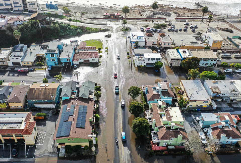 Image: vehicles drive along a flooded street close to the beach on Jan. 10, 2022 in Aptos, Calif. (Mario Tama / Getty Images)