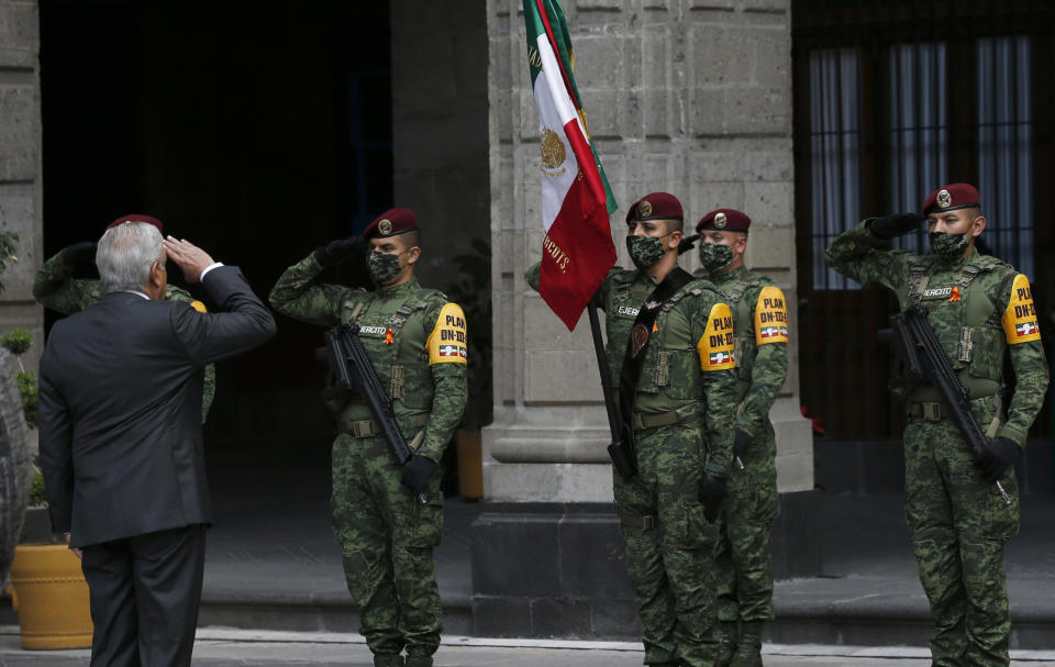 Mexican President Andres Manuel Lopez Obrador salutes the flag during the commemoration of his second anniversary in office, at the National Palace in Mexico City, Tuesday, Dec. 1, 2020. (AP Photo/Marco Ugarte)