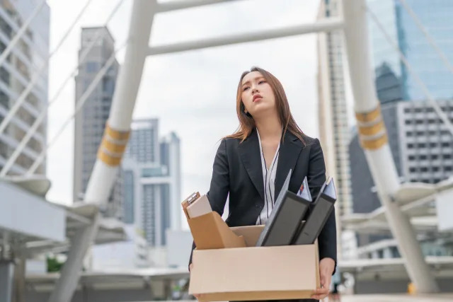 Young asian businesswoman employee holding a box of her personal belongings, illustrating a story on continued rise in job retrenchments.