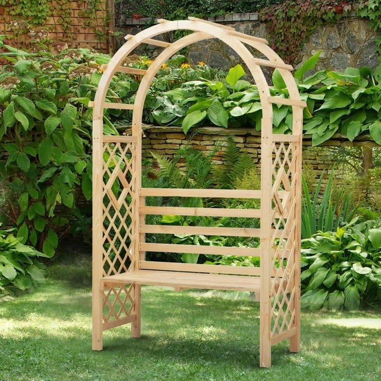 Arbor garden bench with arch and surrounded by garden plants. 