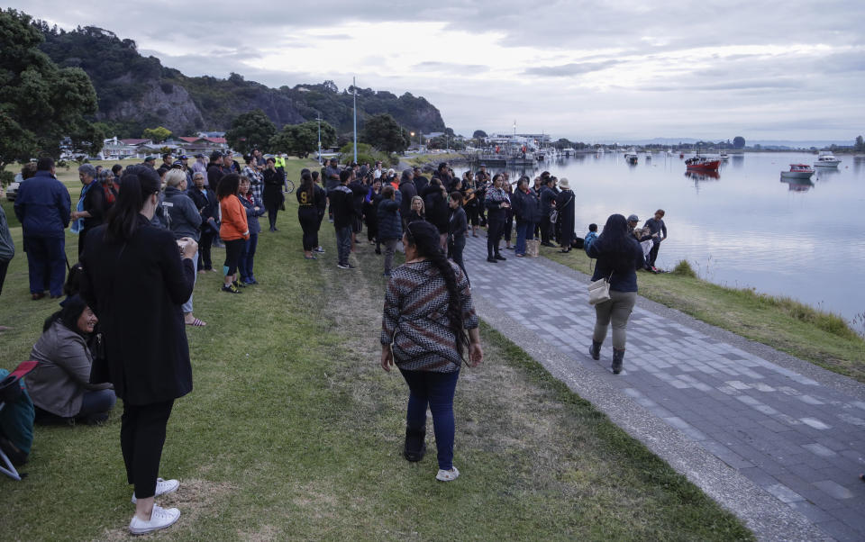 Locals sing during sun rise as they wait for the return of the victims after the White Island eruption to be returned to Whakatane, New Zealand, Friday, Dec. 13, 2019. A team of eight New Zealand military specialists were sent to White Island early Friday to retrieve the bodies of victims after the Dec. 9 eruption. (AP Photo/Mark Baker)