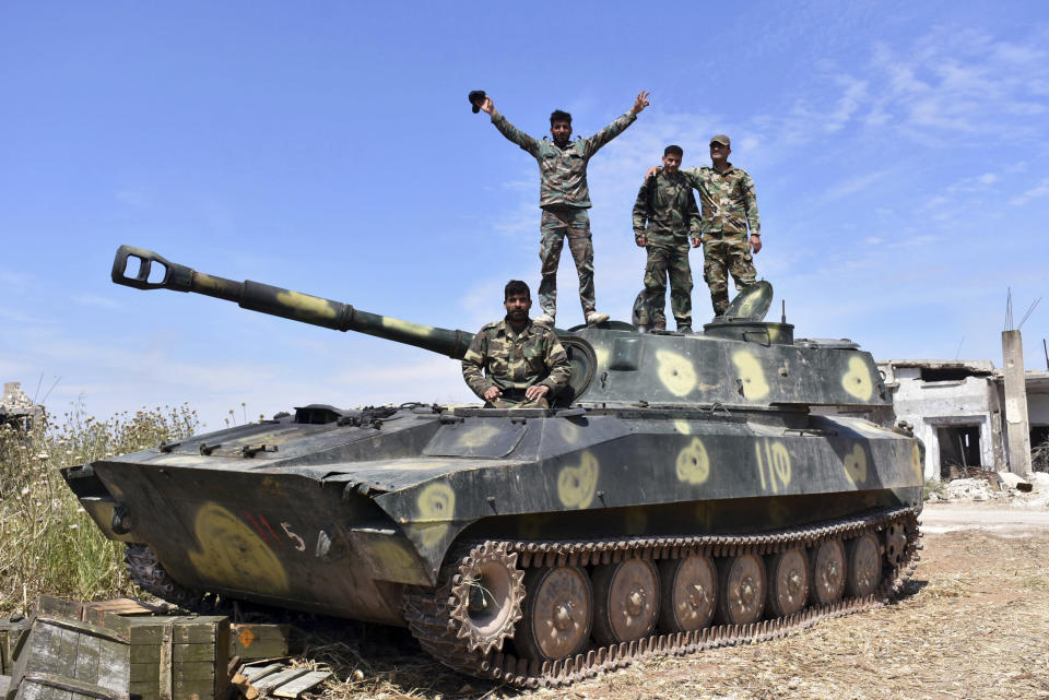 In this photo released by the Syrian official news agency SANA, Syrian army soldiers flash the victory sign as they stand on their tank in the village of Kfar Nabuda, in the countryside of the Hama province on Saturday, May 11, 2019. The Britain-based Syrian Observatory for Human Rights said government forces are now in control of nine villages forming an L shape at the far southern corner of the rebel stronghold. The villages include the strategic village of Kfar Nabuda and the elevated Qalaat Madiq, giving the government troops an advantage over the insurgents. (SANA via AP)