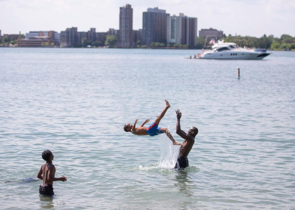 Dimitrius Givens, 32, of Detroit, flips his son Sharod King, 10, into the water while enjoying their Independence Day weekend at the Belle Isle Beach in Detroit on Sunday, July 3, 2022.