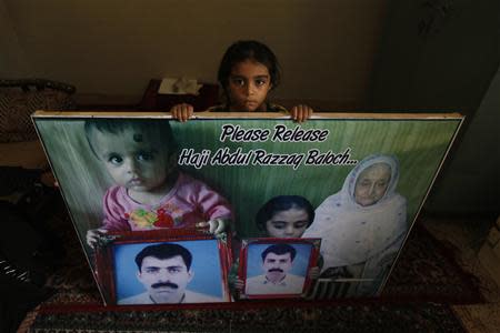 Seven-year-old Zainab, daughter of Abdul Razzaq Baloch, who had been missing since March, displays a poster which depicts herself and her younger sister Sara holding portraits of their father, at her residence in Karachi June 3, 2013. REUTERS/Stringer