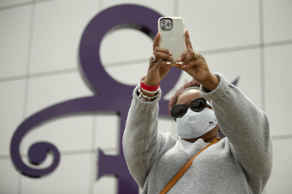 Ruthea Bennett, of Knoxville, Tenn., poses for a selfie in front of the iconic Prince statue, Wednesday, April 21, 2021, outside Paisley Park in Chanhassen, Minn., on the fifth anniversary of his death. (AP Photo/Stacy Bengs)