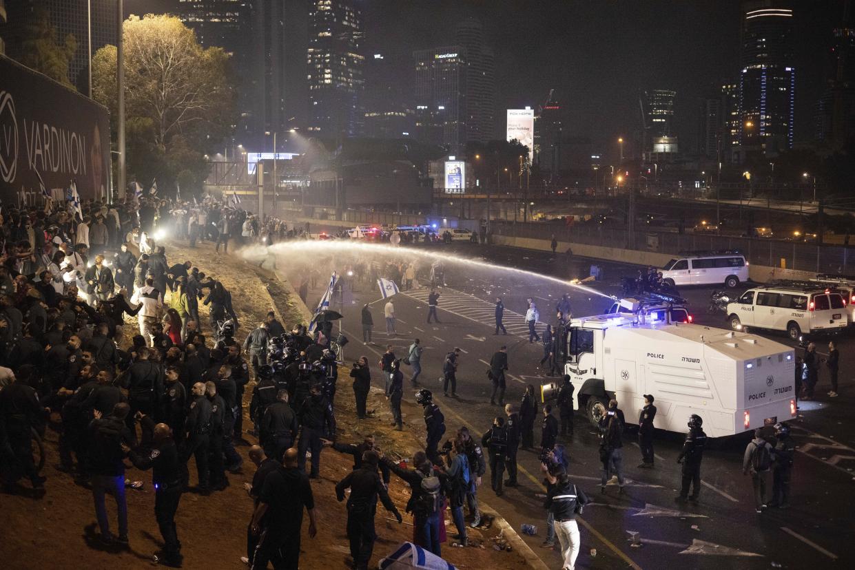 Israeli police use a water cannon to disperse demonstrators blocking a highway during a protest against plans by Prime Minister Benjamin Netanyahu's government to overhaul the judicial system in Tel Aviv, Israel, Monday, March 27, 2023. Tens of thousands of Israelis have poured into the streets across the country in a spontaneous outburst of anger after Prime Minister Benjamin Netanyahu abruptly fired his defense minister for challenging the Israeli leader's judicial overhaul plan. (AP Photo/Oren Ziv)