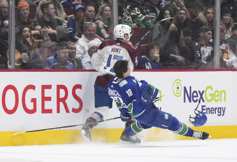 Vancouver Canucks' Jack Studnicka (18) loses his helmet after colliding with Colorado Avalanche's Brad Hunt (17) during the first period of an NHL hockey game Thursday, Jan. 5, 2023, in Vancouver, British Columbia. (Darryl Dyck/The Canadian Press via AP)