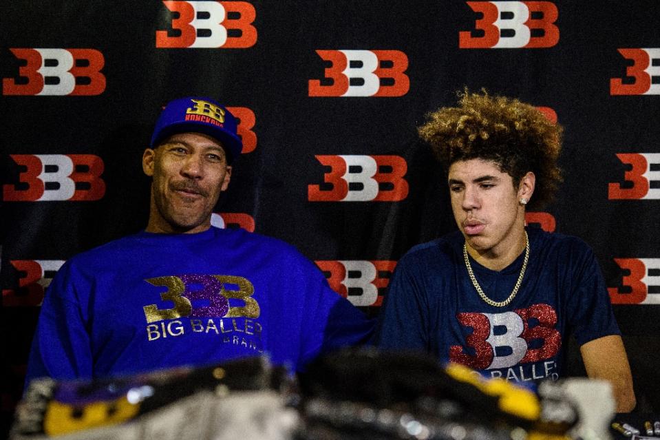 LaVaras Ballas (L), krepšininko Liangelo Ball tėvas ir prekės ženklo Big Baller savininkas, sėdi su kitu sūnumi LaMelo Ballu per reklaminį renginį Honkonge 2017 m. lapkričio 14 d. (AFP nuotrauka / Anthony WALLACE)