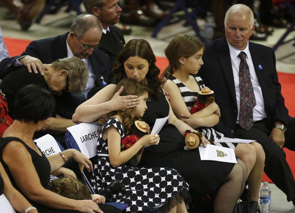 The family of Royal Canadian Mounted Police officer Douglas James Larche, one of three officers who were killed last week, reacts during a regimental funeral Moncton