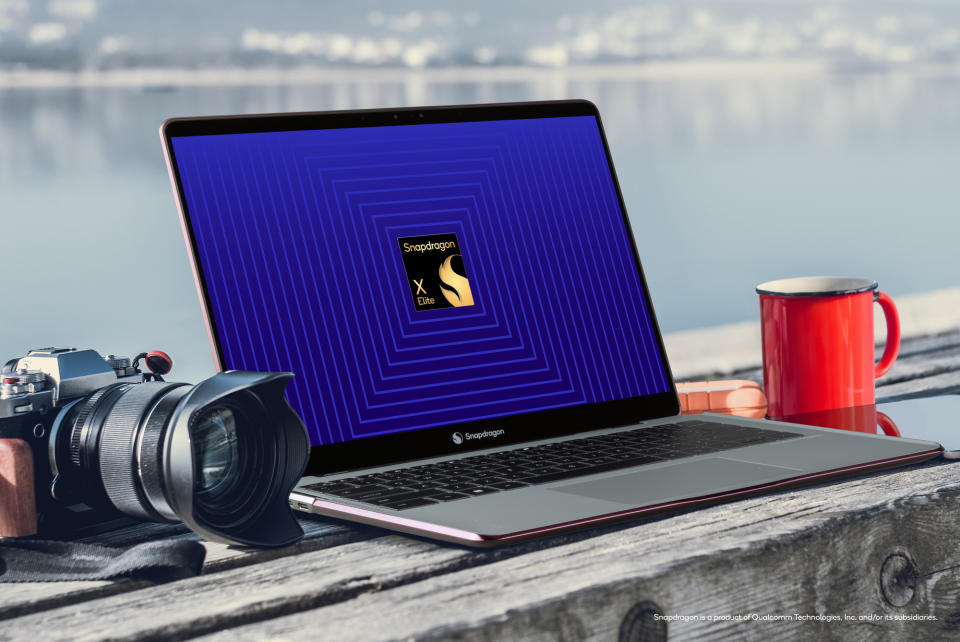 Qualcomm Snapdragon X Elite reference design laptop on a bench with a camera and coffee mug