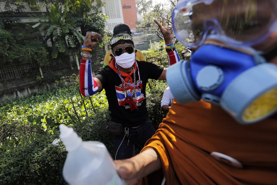 An anti-government protester reacts as a Buddhist monk arrives to help those affected by teargas during clashes with police near the Government House in Bangkok December 2, 2013. Thai Prime Minister Yingluck Shinawatra said on Monday she would "open every door" to find a peaceful solution to a political crisis gripping Bangkok as police used rubber bullets against protesters seeking to topple her government. REUTERS/Damir Sagolj