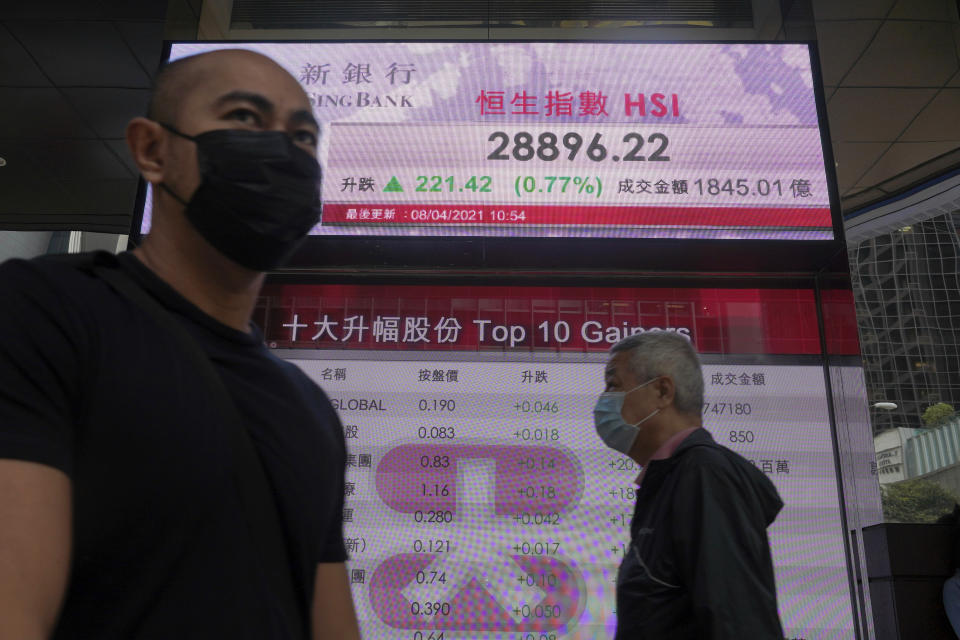 People walk past a bank's electronic board showing the Hong Kong share index in Hong Kong Thursday, April 8, 2021. Shares were mostly higher in Asia on Thursday after a mixed close on Wall Street, where gains for several Big Tech stocks nudged the S&P 500 to a second record high in three days.(AP Photo/Vincent Yu)