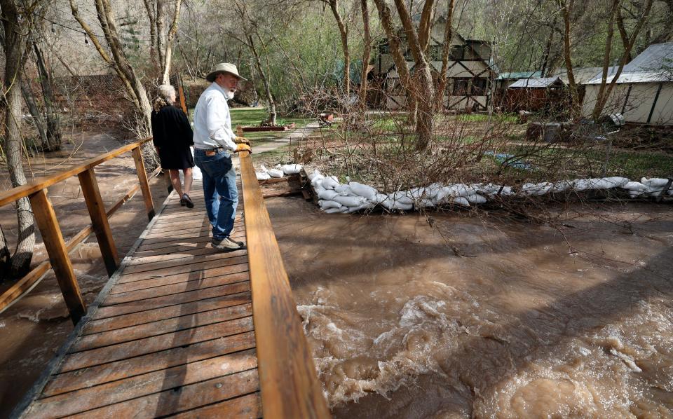 Betsey Collins and Rich Collins cross the bridge to their home as water levels are high in Emigration Creek in Emigration Canyon on Tuesday, May 2, 2023.