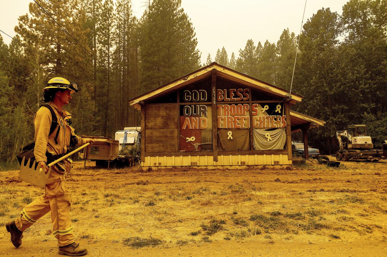 Firefighter Chad Claunch passes a home while preparing for the Dixie Fire's approach, north of Quincy, in Plumas County, Calif. on Sunday, July 25, 2021.