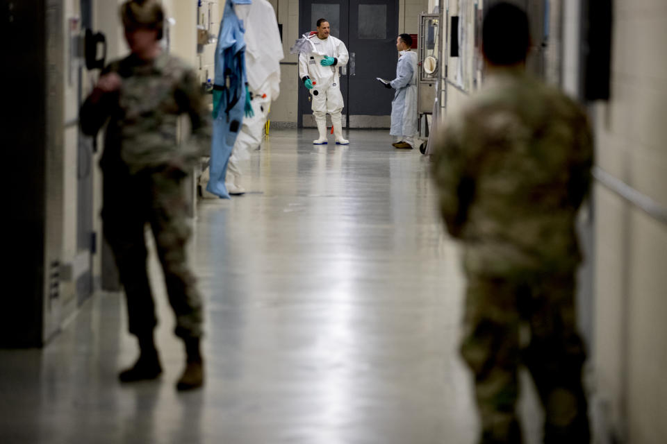 FILE - In this March 19, 2020 file photo, biological science specialists, background, wear biosafety protective clothing for handling viral diseases at U.S. Army Medical Research and Development Command at Fort Detrick in Frederick, Md. On March 9, 2020, a public WeChat account called "Happy Reading List" reposted an essay claiming the U.S. military created SARS-CoV-2, the virus that causes COVID-19, at a lab in Fort Detrick and loosed it in China during the Military World Games, an international competition for military athletes, held in Wuhan in October 2019. (AP Photo/Andrew Harnik)