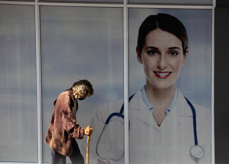 A man passes doctors consulting rooms in Johannesburg Friday, April 16, 2021. South Africa took the first step to launch online registrations for the vaccination of people who are 60 years and older as it prepares for the second phase of its vaccination programme expected to start next month. (AP Photo/Denis Farrell)