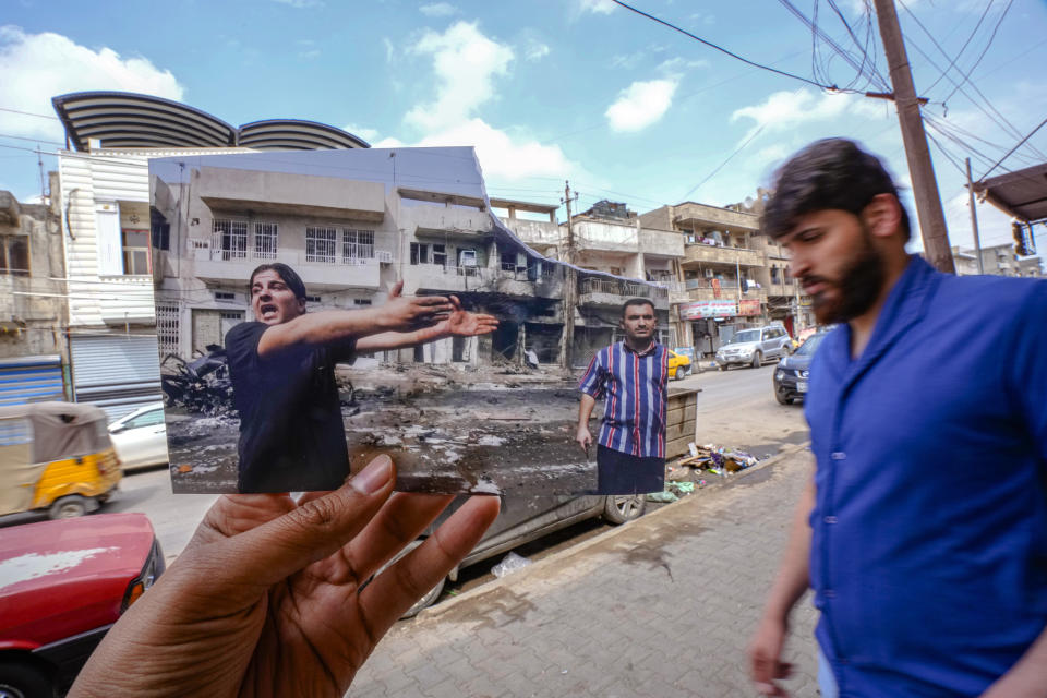 A photograph of an Iraqi shouting after series of bombs exploded in a shopping district in a mainly Christian neighborhood of of Camp Sara in Baghdad on Wednesday, killing at over a dozen and wounding almost a hundred Wednesday Oct. 4, 2006, is inserted into the scene at the same location Tuesday, March 21, 2023, 20 years after the U.S. led invasion on Iraq and subsequent war. (AP Photo/Hadi Mizban)