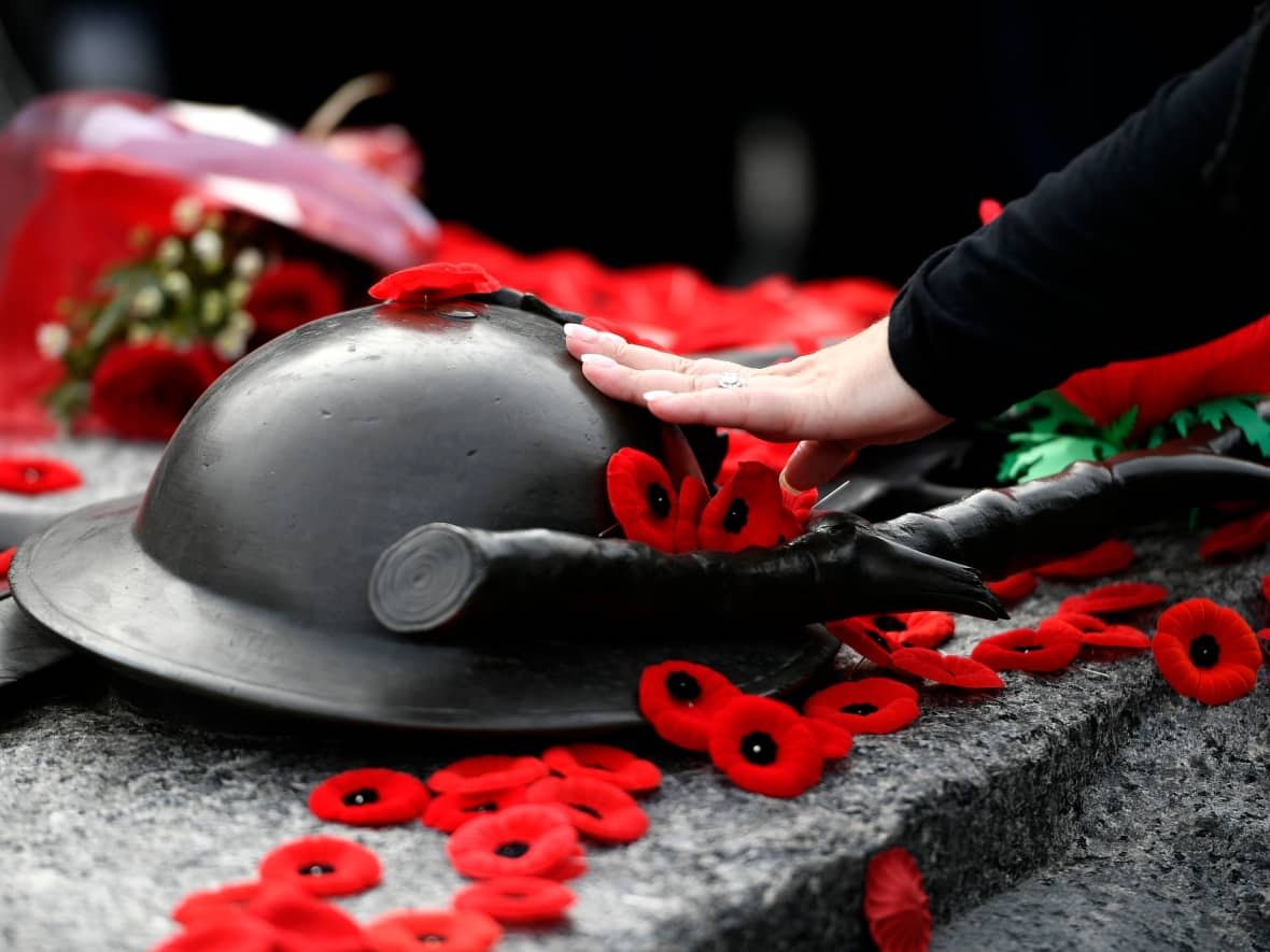 A person touches the helmet on the Tomb of the Unknown Soldier after laying a poppy, at the National War Memorial after the National Remembrance Day Ceremony in Ottawa, on Friday, Nov. 11, 2022.  (The Canadian Press/Justin Tang - image credit)