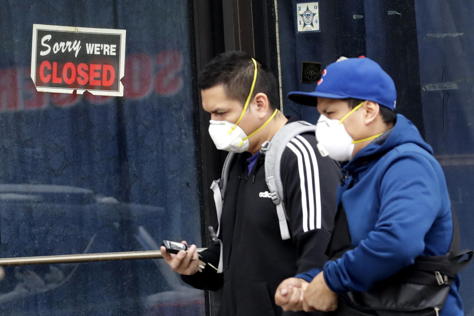 FILE - In this April 15, 2020, file photo, two people walk past a closed sign at a retail store in Chicago. Ever since the U.S. government launched its emergency lending program for small businesses on April 3, there have been complaints that bigger companies had their loans approved and disbursed more quickly. There is now evidence to back up those complaints. (AP Photo/Nam Y. Huh, File)