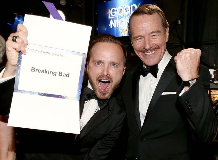 Aaron Paul and Bryan Cranston holding their award envelope