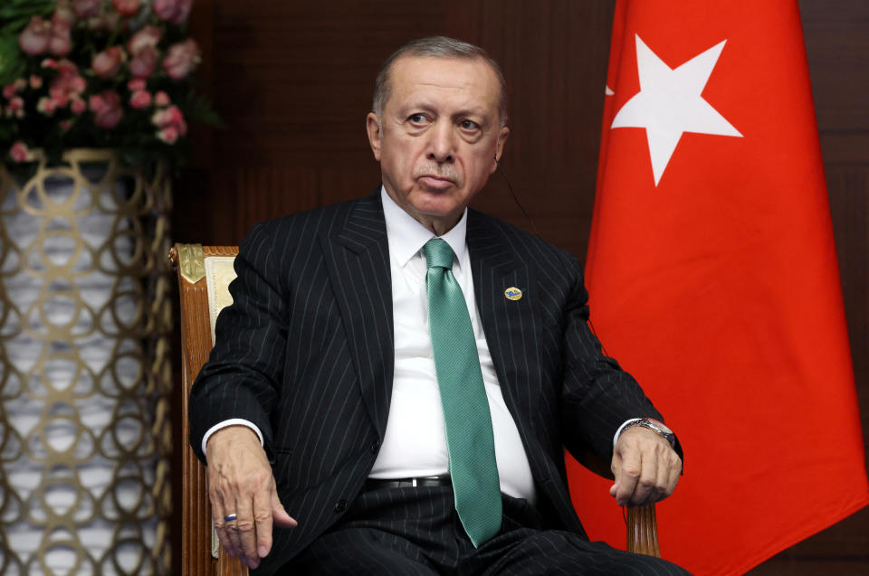 Turkey's President Recep Tayyip Erdogan, seated, with the Turkish flag beside him.