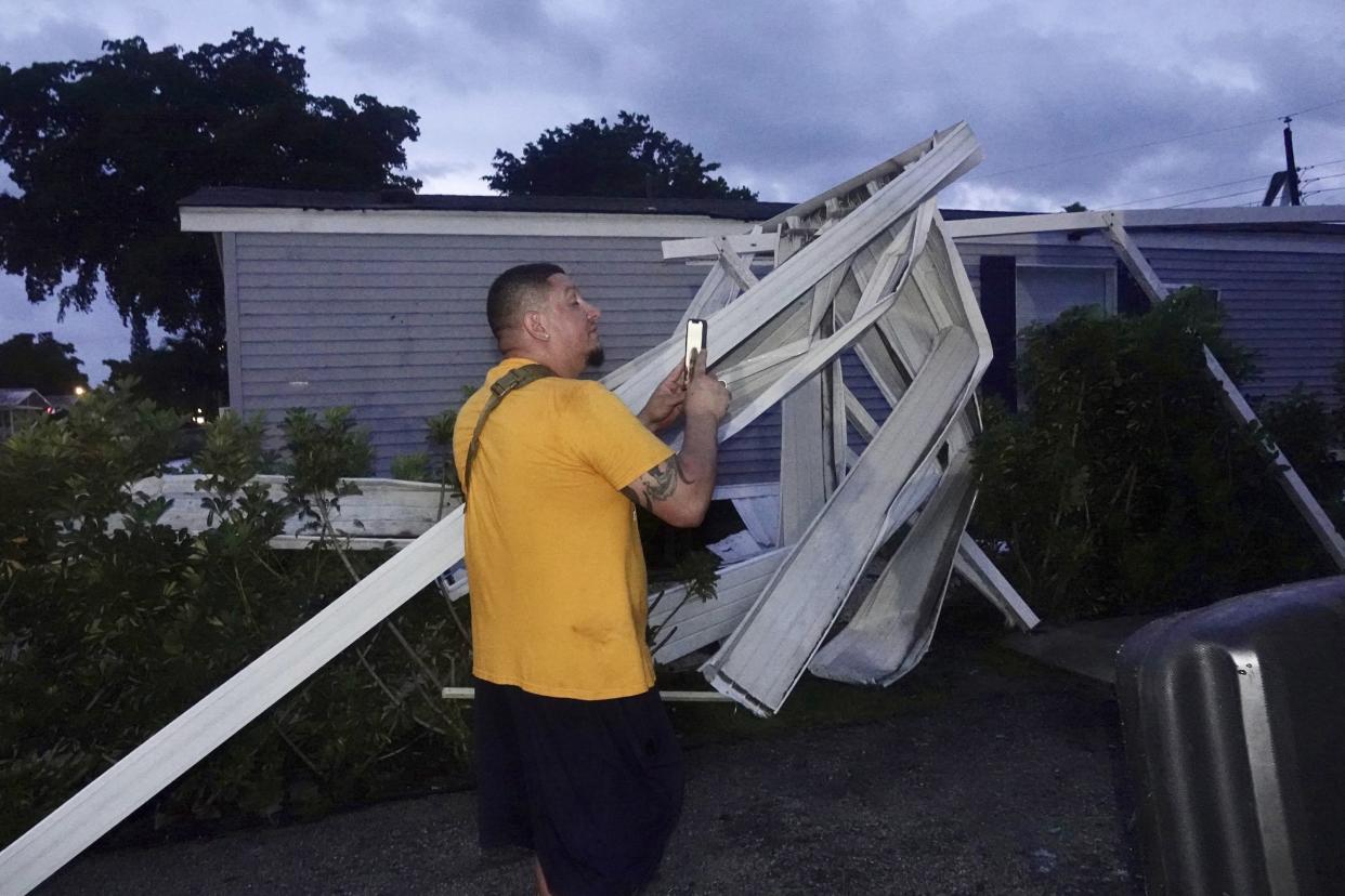Ivan Mendoza surveys the damage at his mobile home in Davie, Fla., early Wednesday, Sept. 28, 2022.