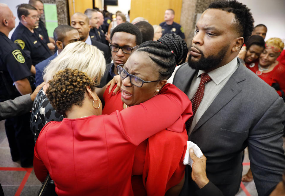 Botham Jean's mother, Allison Jean, center, escorted by civil rights attorney Lee Merritt, right,, is hugged by family members outside the courtroom after fired Dallas police officer Amber Guyger was found guilty of murder, Tuesday, Oct. 1, 2019, in Dallas. Guyger shot and killed Botham Jean, an unarmed 26-year-old neighbor in his own apartment last year. She told police she thought his apartment was her own and that he was an intruder. (Tom Fox/The Dallas Morning News via AP, Pool)