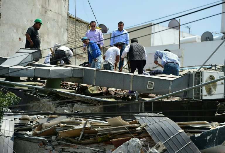 People look through debris of a building that collapsed in a powerful earthquake that shook Mexico City