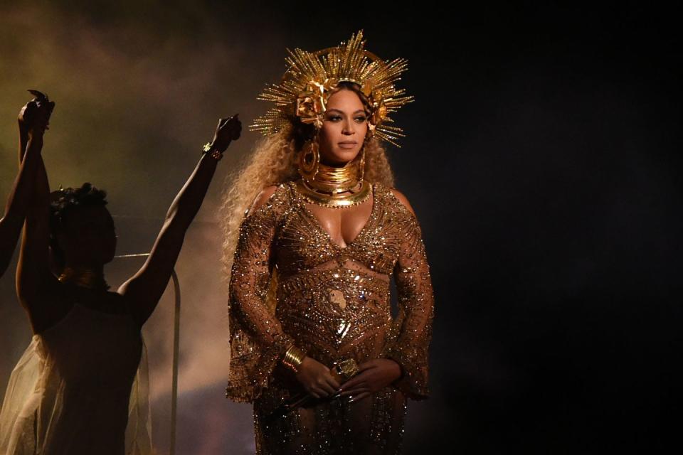 beyoncé performing on a stage while wearing a jewel encrusted gown and golden headpiece