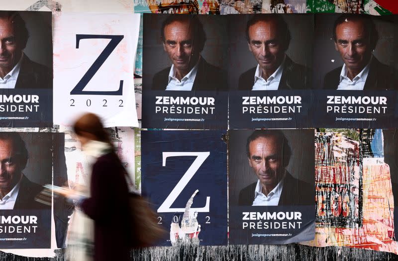 A woman walks past posters in support of French far-right commentator Eric Zemmour in Paris