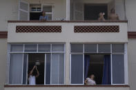 Residentes de un edificio de Río de Janeiro observan y sacan fotos al bombero Elielson Silva mientras toca su trompeta desde la escalera desplegada de su camión el 5 de abril del 2020. (AP Photo/Leo Correa)