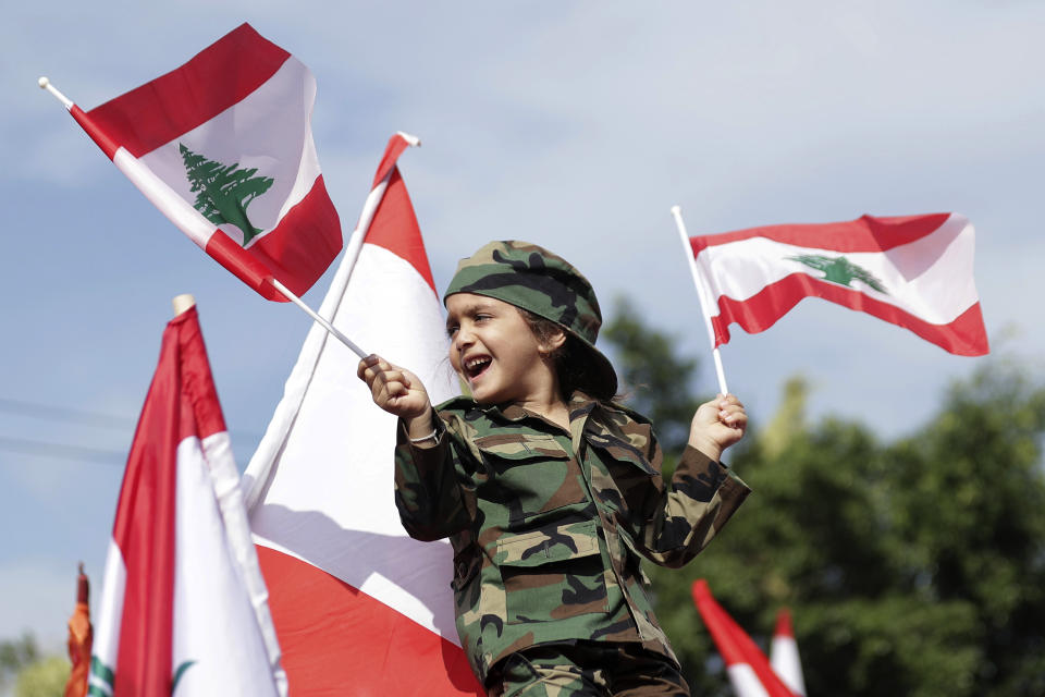 A youth holds Lebanese flags during a protest in support of Lebanese President Michel Aoun, near the presidential palace in the Beirut suburb of Baabda, Lebanon, Sunday, Nov. 3, 2019. Thousands of people are marching to show their support for Aoun and his proposed political reforms that come after more than two weeks of widespread anti-government demonstrations. (AP Photo/Hassan Ammar)