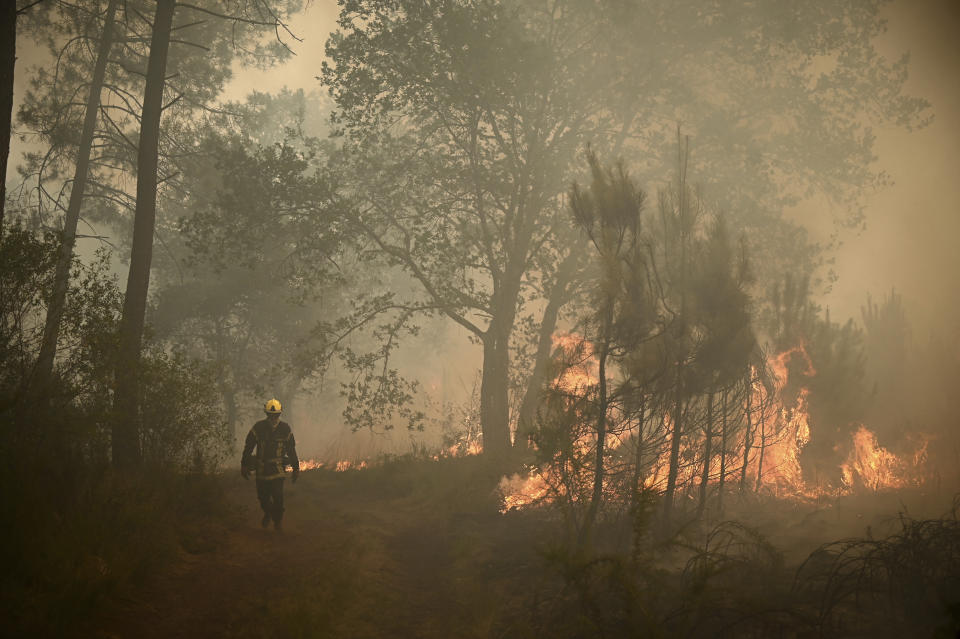 A firefighter walks among flames at a forest fire near Louchats, 35 kms (22 miles) from Landiras in Gironde, southwestern France, Monday, July 18, 2022. France scrambled more water-bombing planes and hundreds more firefighters to combat spreading wildfires that were being fed Monday by hot swirling winds from a searing heat wave broiling much of Europe. With winds changing direction, authorities in southwestern France announced plans to evacuate more towns and move out 3,500 people at risk of finding themselves in the path of the raging flames. (Phillippe Lopez)