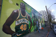 An artist who goes by the name "Weirdo" puts the finishing touches on a giant mural on an outside wall of Shawn Kemp's Cannabis, the marijuana dispensary owned by Shawn Kemp, a former NBA basketball player for the Seattle SuperSonics and several other teams, and other business partners, Friday, Oct. 30, 2020, prior to the store's grand opening in downtown Seattle. (AP Photo/Ted S. Warren)