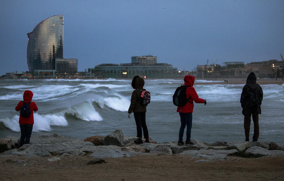 Tourists look at the waves at the Mediterranean sea during strong winds in Barcelona, Spain, Sunday, Jan. 19, 2020. (AP Photo/Emilio Morenatti)