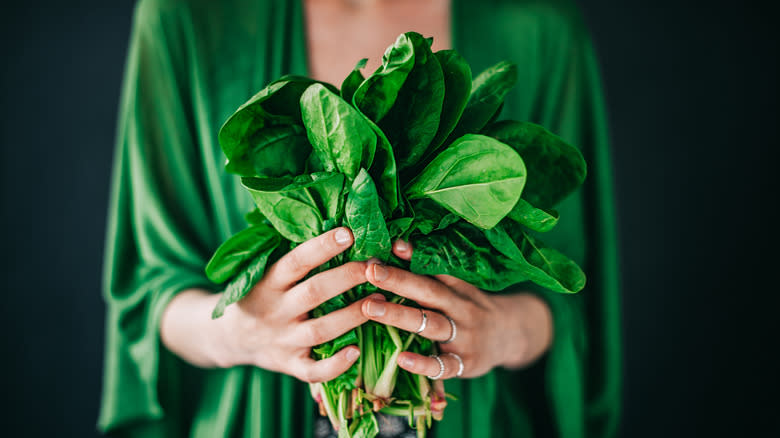 woman holding bunch of greens