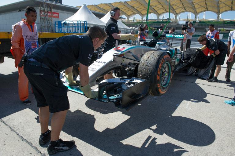 Lewis Hamilton's Mercedes is hoisted off a truck to the pit area after experiencing mechanical problems during the first practice session at the Malaysian GP in Sepang on March 27, 2015