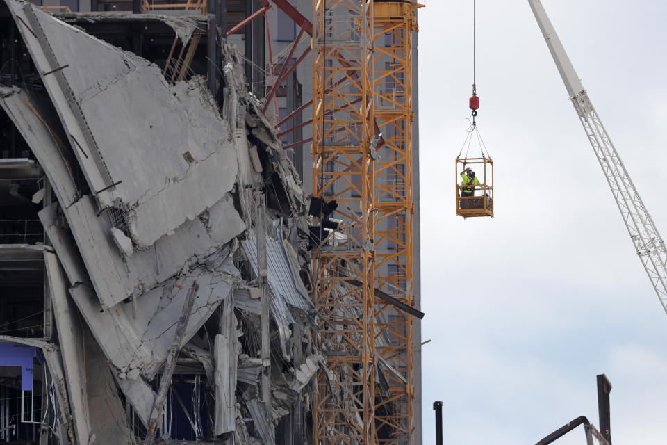 Workers are raised in a crane bucket to prepare two unstable cranes for implosion at the collapse site of the Hard Rock Hotel, which underwent a partial, major collapse while under construction last Sat., Oct., 12, in New Orleans, Saturday, Oct. 19, 2019. (AP Photo/Gerald Herbert)