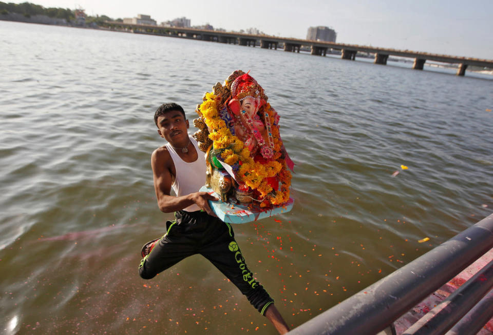 A devotee carrying an idol of the Hindu god Ganesh jumps into the Sabarmati river