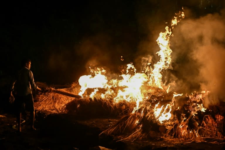 A man torches funeral pyres of victims who died after consuming toxic alcohol during a mass cremation in Kallakurichi district of India's Tamil Nadu state (R.Satish BABU)